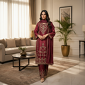 Woman in a maroon embroidered traditional outfit standing in a living room.